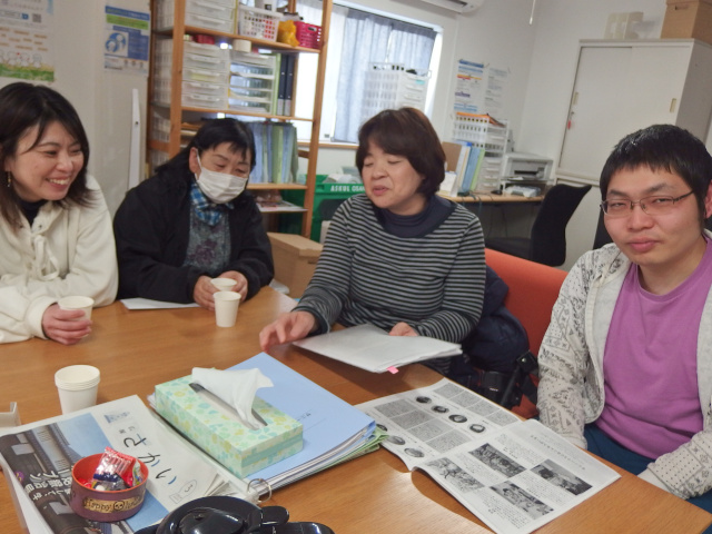 男女が集まり、楽しく話をしている。メンバー・スタッフが入り混じっている。椅子に座っている。飲み物を飲んでいる。