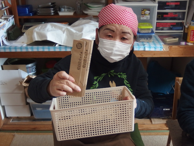 箸袋を持つ高齢の女性。カメラに向かって箸袋をアピールしている。