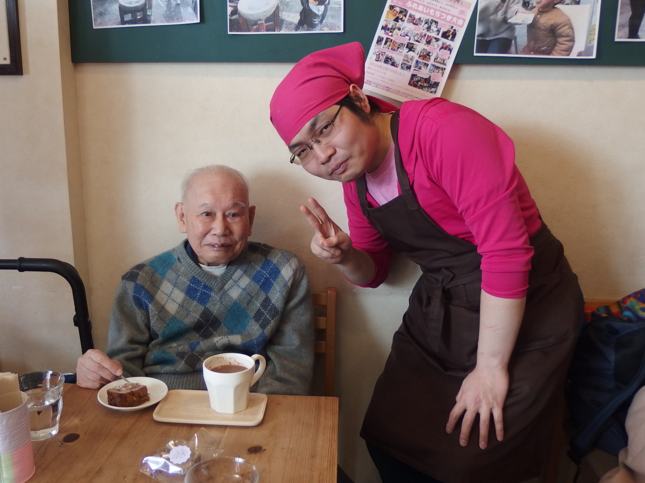 2人の女性のお客と女性のメンバーの写真。ご飯を食べながらピースしている。お客の女性は口元をぬいぐるみで隠している。犬のぬいぐるみだ。