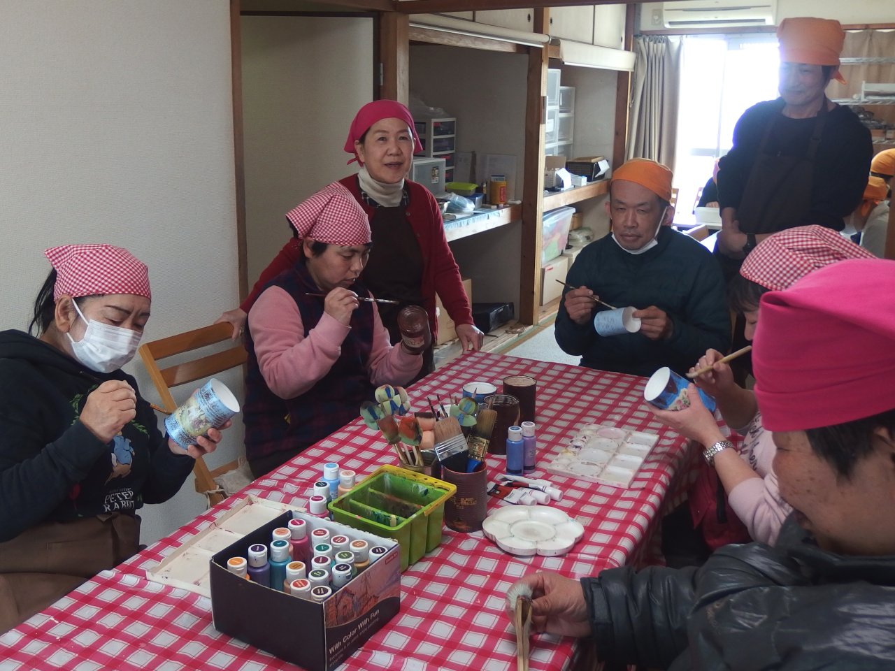 リメイク缶を5人ほどのメンバーで作っている写真。缶の色塗りをしている。